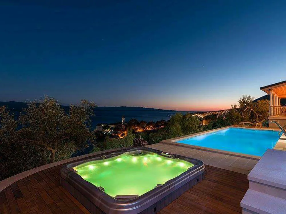 Hidromasažna kada i bazen na drvenoj terasi u sumrak — Villa Ventula, Bol