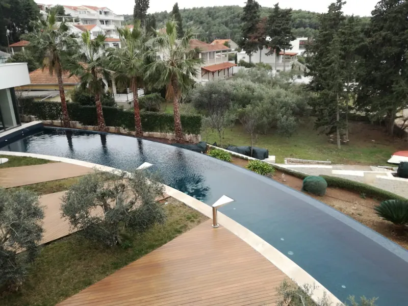Vodena površina uz šetnicu s palmama — bazen izveden kao kanal uz vilu